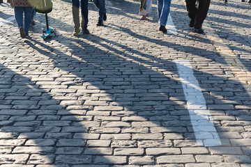 Pedestrians on cobblestone pavement, shadows, people traffic