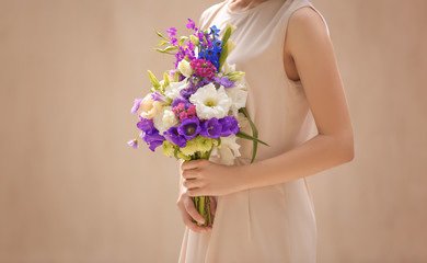 Woman holding bouquet of beautiful flowers on light background
