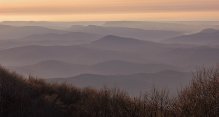 Silhouettes of mountains in fog to the horizon during sunset. Pattern with empty space for text