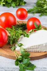 White cheese, knife, parsley, tomatoes on a wooden boards background