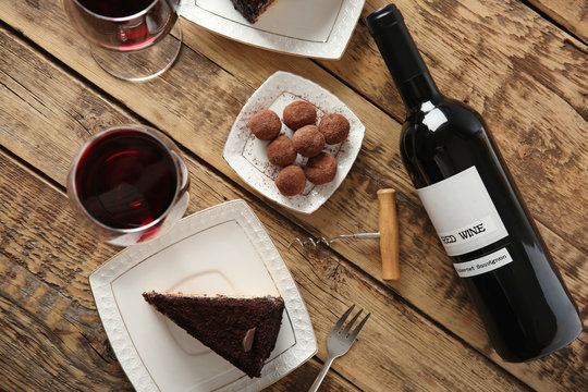 Red Wine, Chocolate Truffles And Tasty Cake On Wooden Background