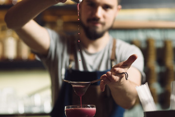 Young male bartender preparing an alcohol cocktail