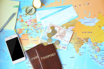 Composition with smartphone, passports, money and arrival cards on world map background