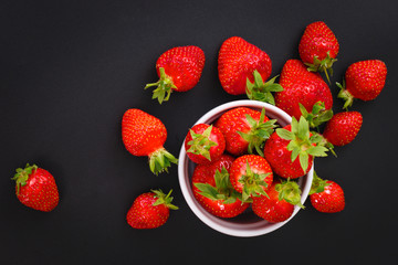 Organic fresh strawberries fruit in white cup on black background