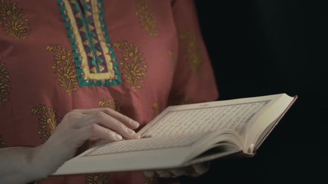 Women's hands leaf through the pages of the Koran