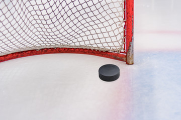 Hockey puck in front of the gate in front of the hockey game on ice