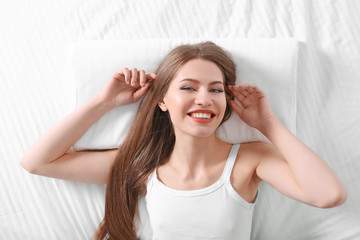 Young woman lying on bed with orthopedic pillow. Healthy posture concept