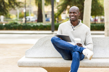 Black young man with tablet computer and take away coffee