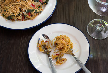 Stir fried Clams and Spaghetti with chili paste in the white dish and in dish divide food with water glass on table