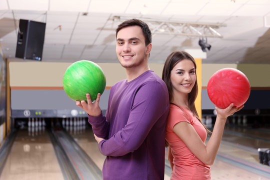 Young man and woman having fun at bowling club
