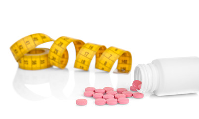 Weight loss concept. Measuring tape and pills on white background