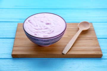 Bowl with yogurt on wooden board