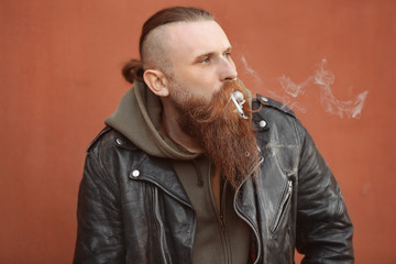 Bearded man smoking weed outdoors on color background