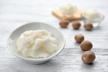 Shea butter in bowl on wooden background