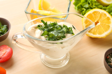 Delicious mayonnaise in gravy boat on kitchen table, closeup