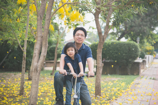 Asian  father and son riding bicycle