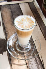 hot coffee latte art with glass on wooden table.