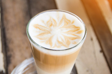 hot coffee latte art with glass on wooden table.