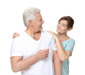 Senior man with toothbrush and his wife on white background