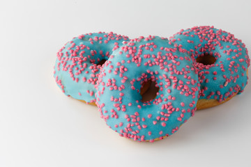 Donuts with blue glaze and pink sprinkles isolated on white background. Top view.