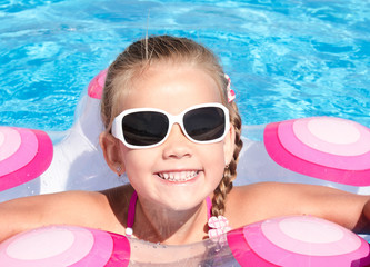 Fototapeta na wymiar Smiling little girl in swimming pool