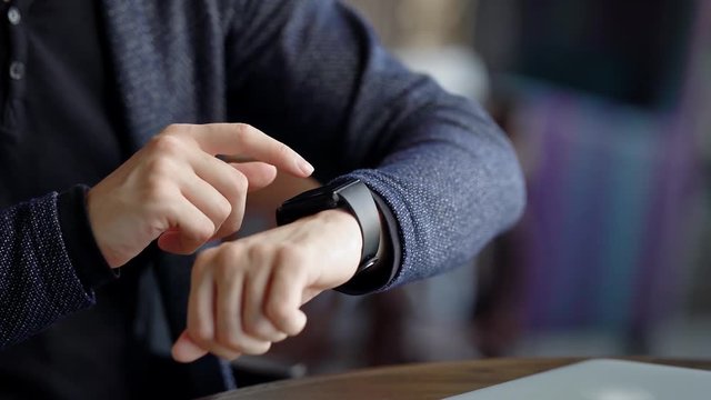 Crop shot of man checking time. Crop shot of male using smartwatch while sitting in cafe.