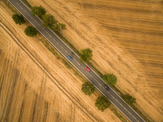 Aerial view of a country road amid fields with a car on it
