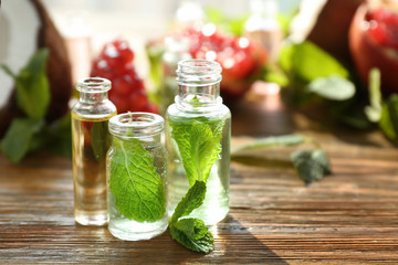 Beautiful composition with perfume bottles and mint on wooden background