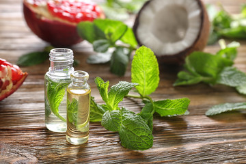 Beautiful composition with perfume bottles and mint on wooden background