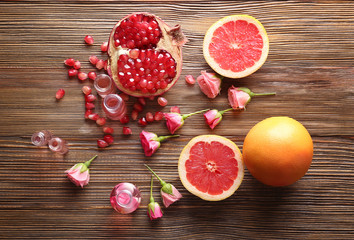 Beautiful composition with perfume bottles, roses and fresh fruits on wooden table