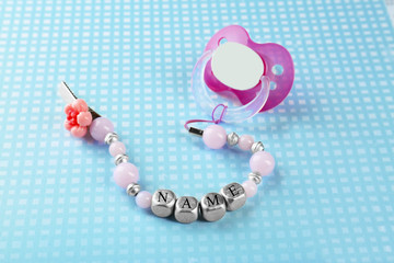 Pacifier clip with place for baby name and dummy on table