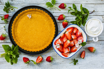Delicious sponge cake with fresh strawberries on a wooden background.
