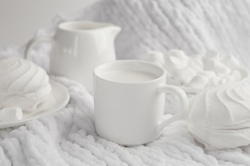 Fototapeta na wymiar plate of marshmellow, white zephyr and milk in coffee cup on white background, still life in white. monochrome setting, high key