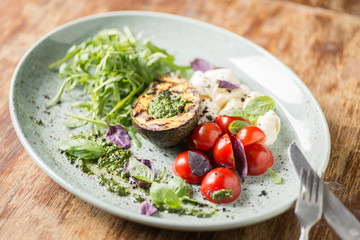 Italian appetizer with avocado, mozzarella, tomatoes and pesto sauce