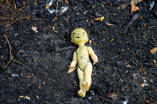 Abandoned old broken doll on grey ash background
