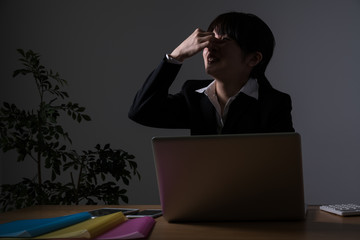残業をするビジネスウーマン、眼精疲労