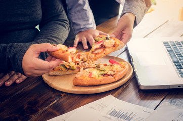 Business team is eating pizza at work while working