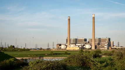 Fototapeta na wymiar Tilbury Power Stations. The decommissioned coal power stations with pylons behind feeding energy into the UK National Grid electricity network.