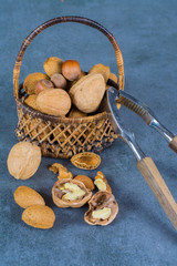 Nuts mix in shell - walnuts, hazel and almonds with nut chaker on grey concrete backgrund