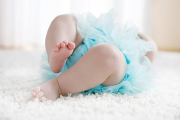 Close-up of legs and feet of baby girl on white background wearing turquoise tutu skirt. © Irina Schmidt