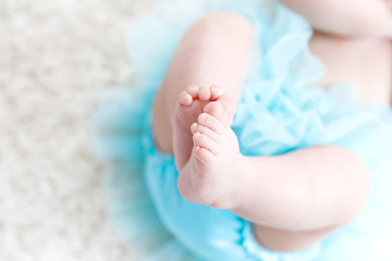 Close-up of legs and feet of baby girl on white background wearing turquoise tutu skirt. © Irina Schmidt