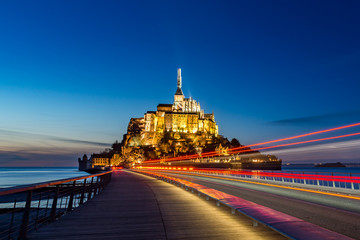 Le Mont saint michel Panoramic of famous historic Illuminated architecture panoramic beautiful postcard view with red light trail at Night in Summer Low Tide from the bridge with reflection, France