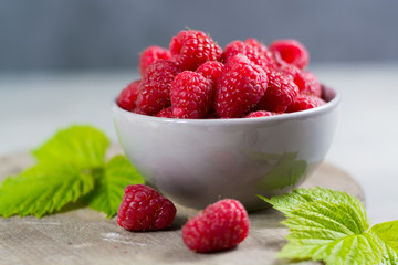 Fresh organic fruit - ripe raspberry with leaves on wood background