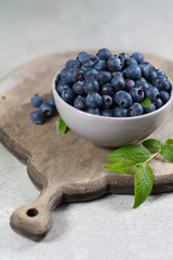 Freshly picked juicy blueberries with green leaves on rustic table. Bilberry on wooden Background. Blueberry antioxidant. Concept for healthy eating and nutrition