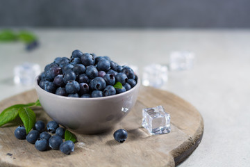 Freshly picked juicy blueberries with green leaves on rustic table. Bilberry on wooden Background. Blueberry antioxidant. Concept for healthy eating and nutrition