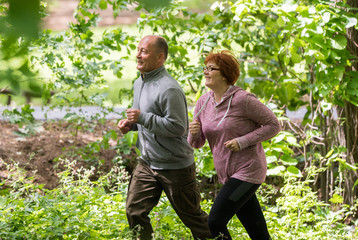 Older couple  wearing sportswear and running in forest at mountain