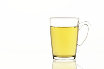 Tea mug with green tea on white isolated background, glass dish for liquids concept