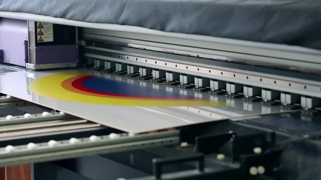 Working industrial large format UV printer for printing on big plastic panel. Printer machine inkjet during production.
