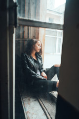 beautiful woman poses on a window sill