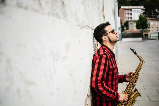 Young musician holding saxophone while standing outdoors